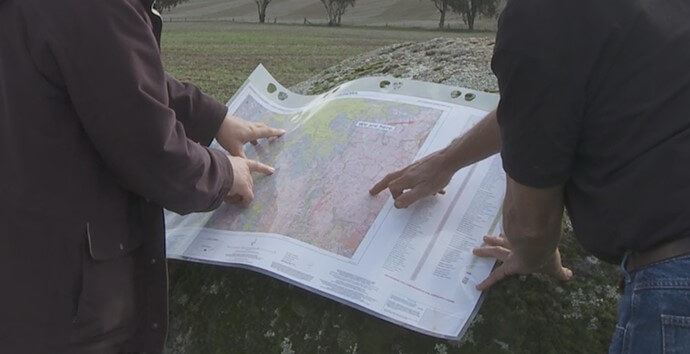 Two men inspecting a map outdoors.