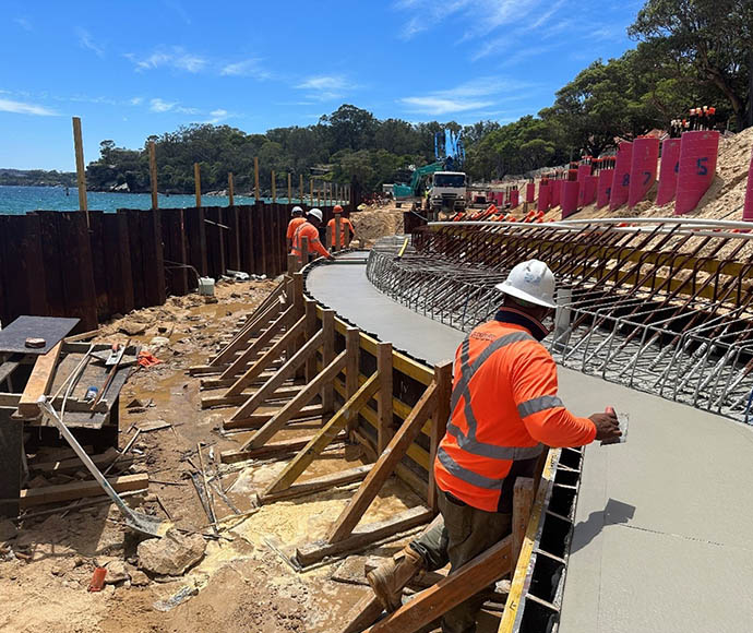 Workers pouring concrete for the capping beam at Nielsen Park, Sydney Harbour National Park, with construction materials and equipment visible on-site.